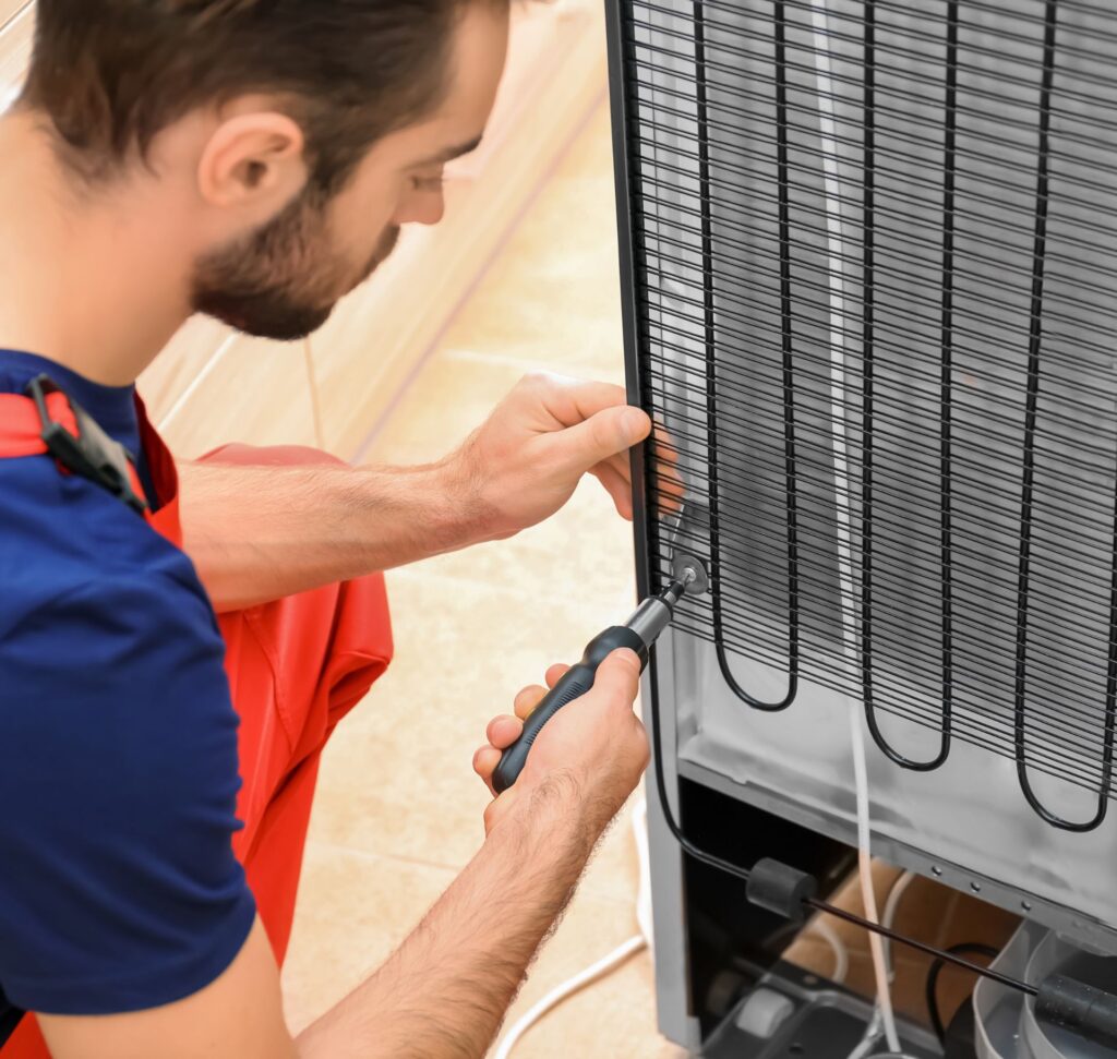 Man fixing refrigerator coils