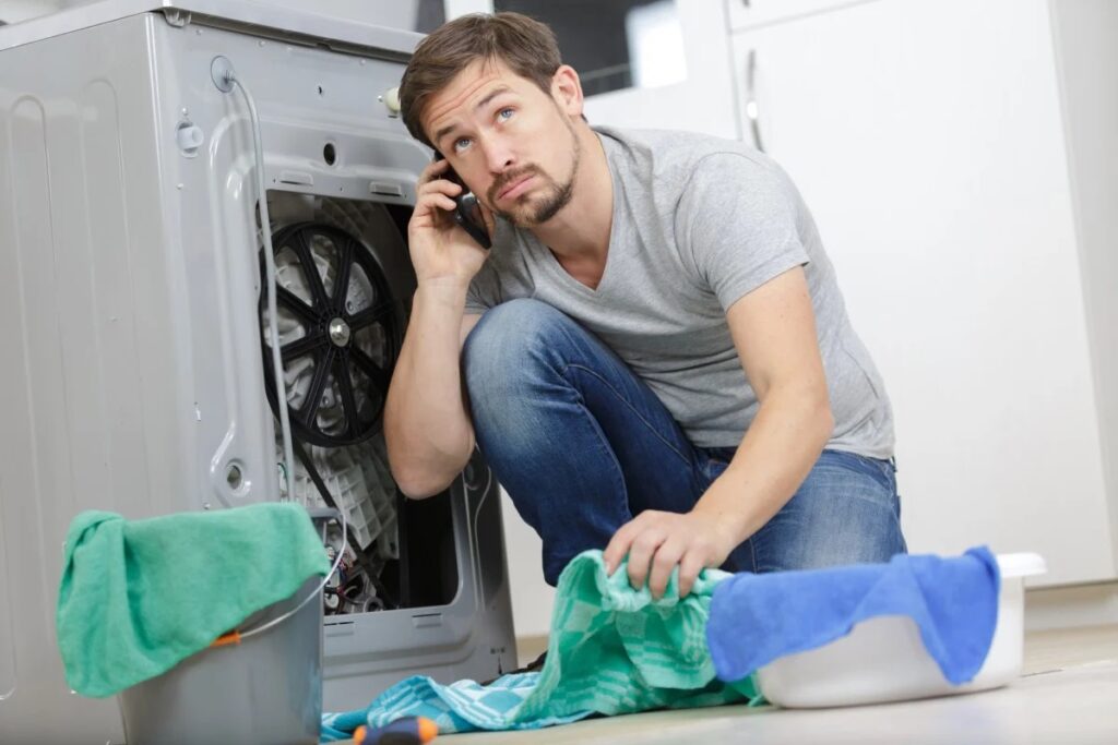 man calling on his phone in front of washer
