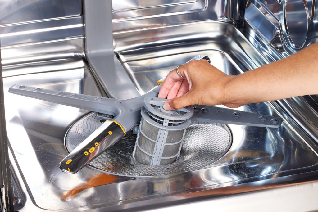 a person cleaning a dishwasher filter