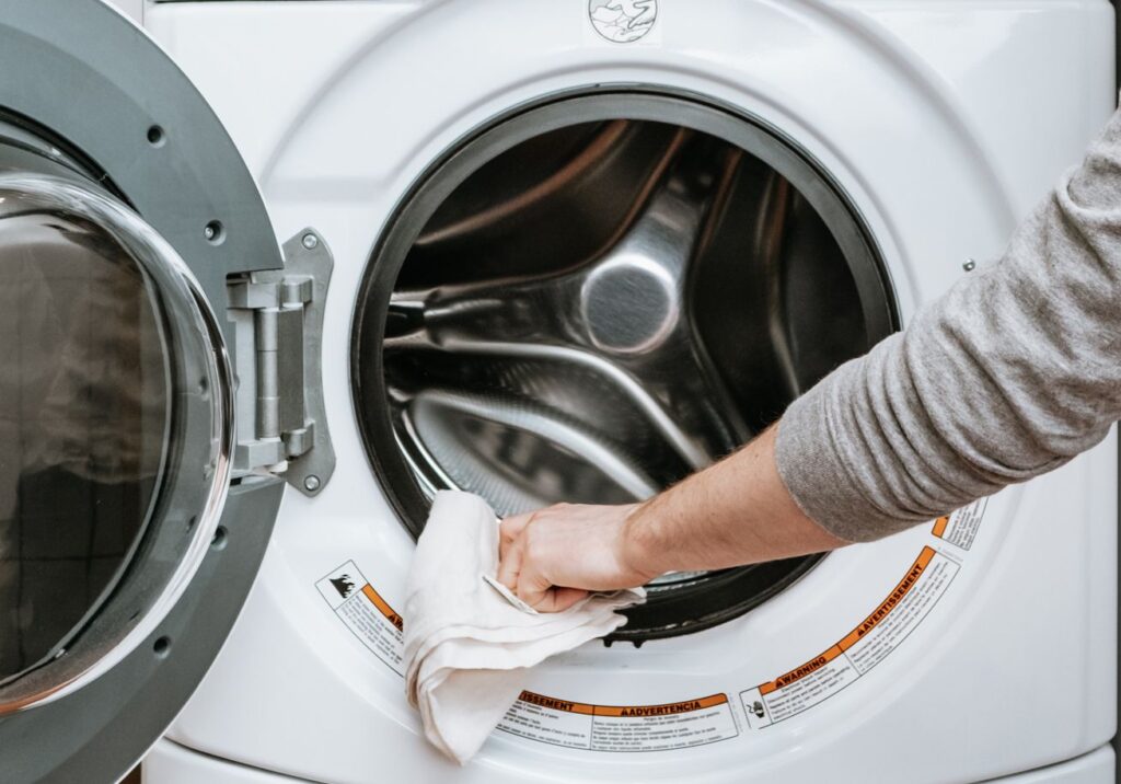 a person cleaning the rubber gasket and drum of a front-loading washing machine