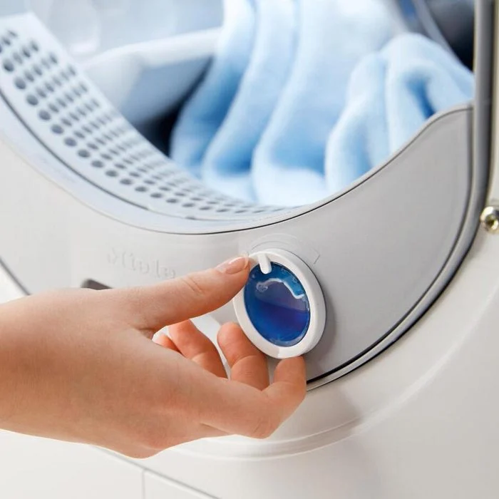 a person's hand adjusting the dial on a heat pump tumble dryer