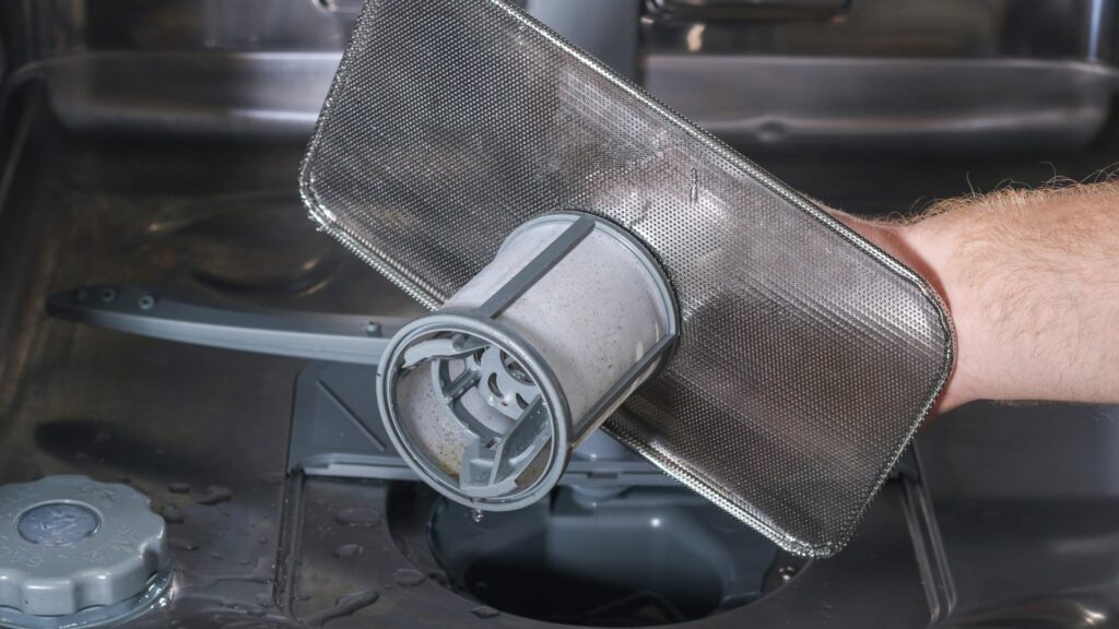a person holding and removing a dishwasher filter