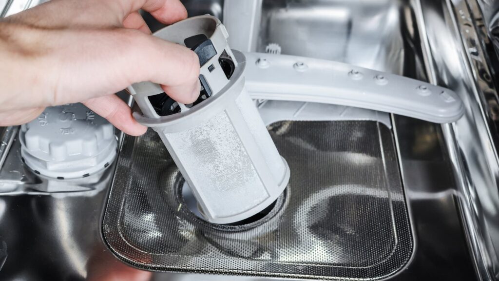a person removing or cleaning a dishwasher filter