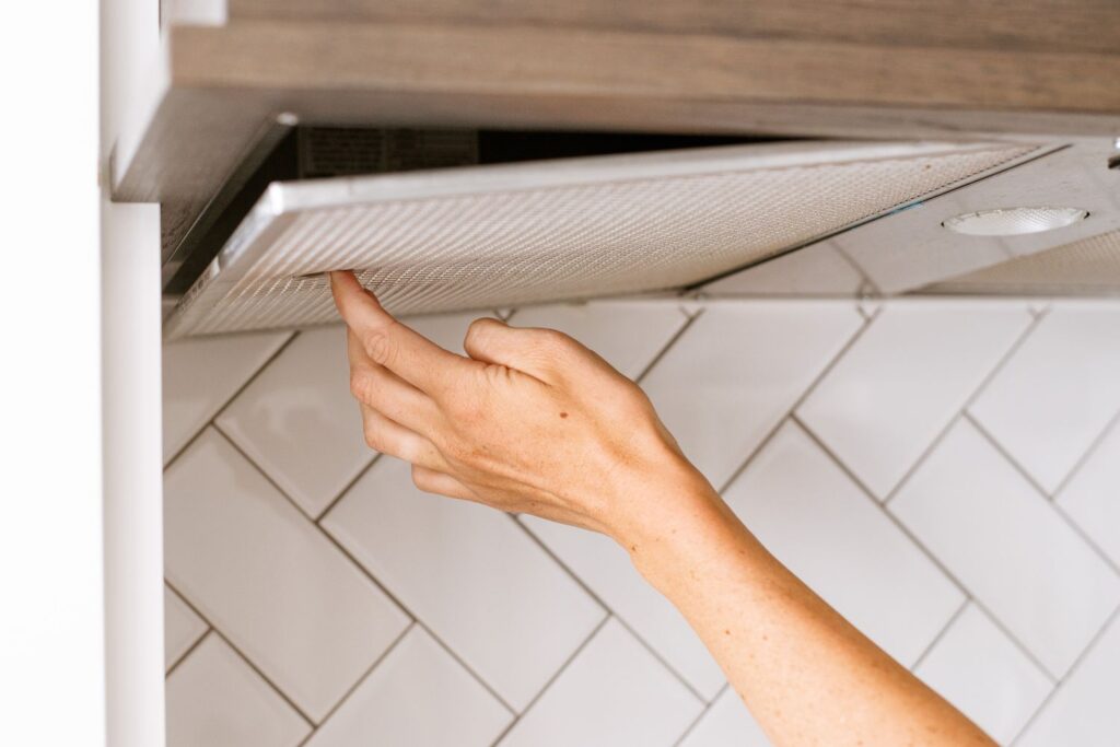 a person's hand pressing on a range hood filter