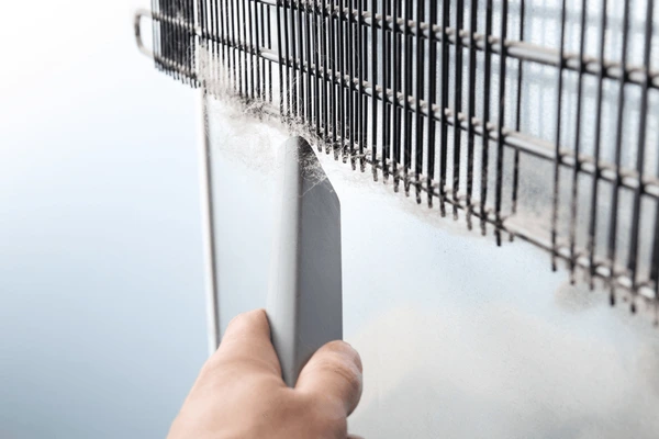 a person cleaning the condenser coils of a refrigerator