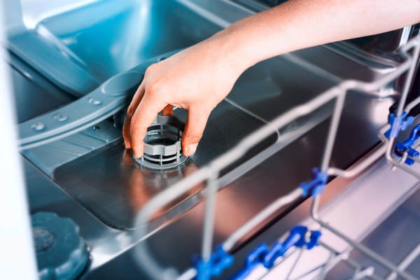 a person's hand removing or cleaning a dishwasher filter
