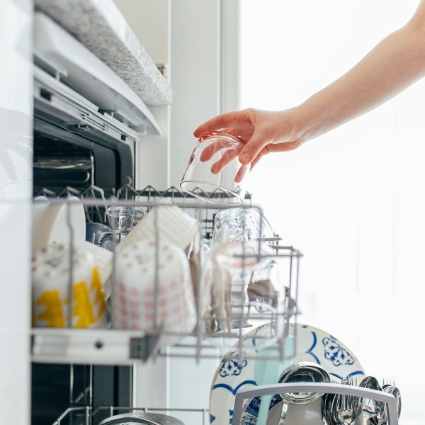 a person loading a glass into a dishwasher