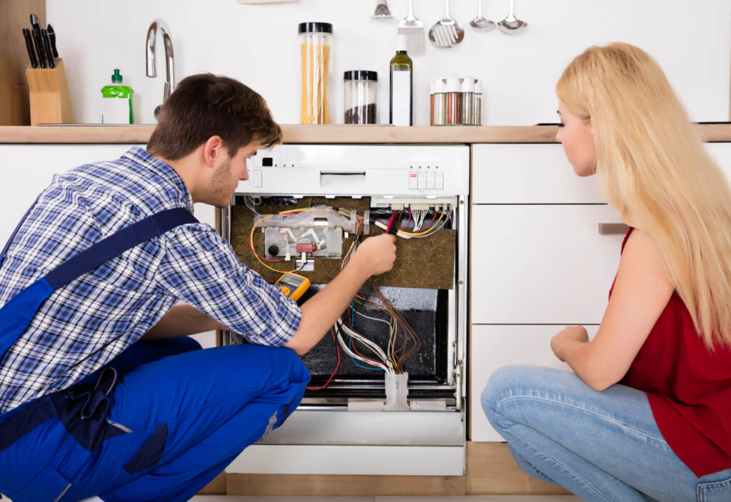 repairman fixing the appliance of the girl in the kitchen