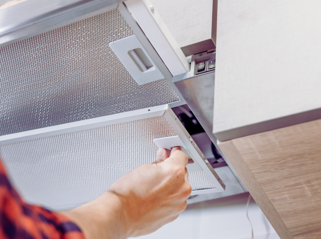 a person removing a filter from a range hood