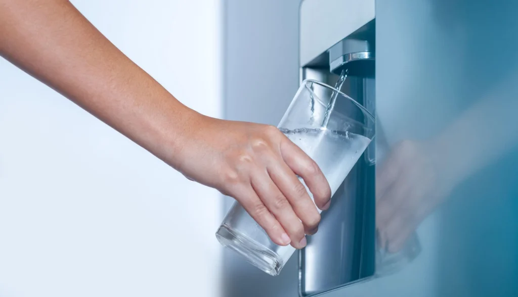 a person dispensing water from a refrigerator's built-in water dispenser