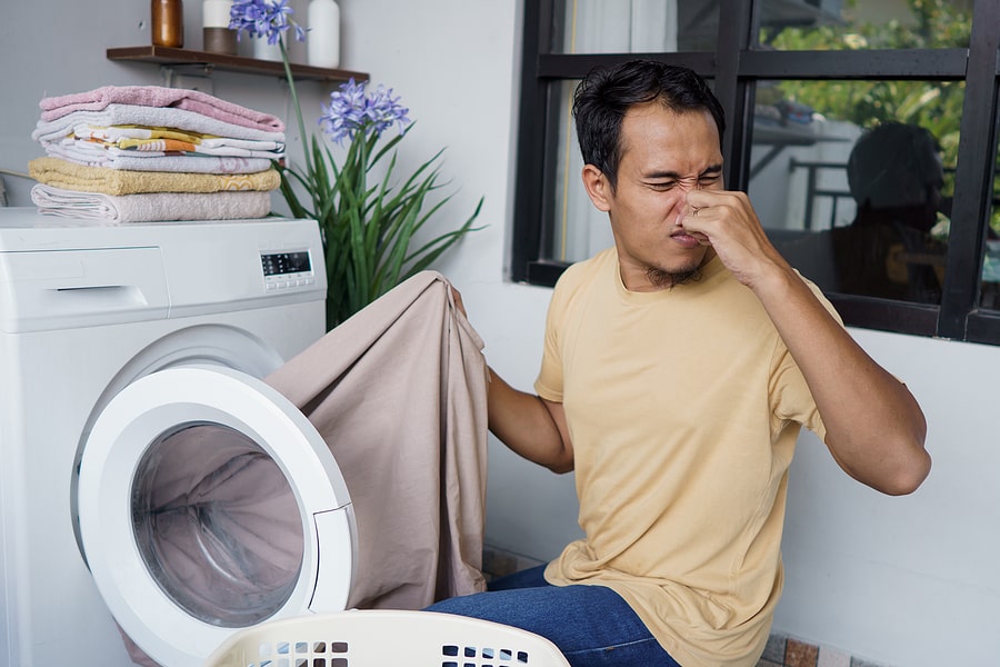 a boy smelling a bad in his washer