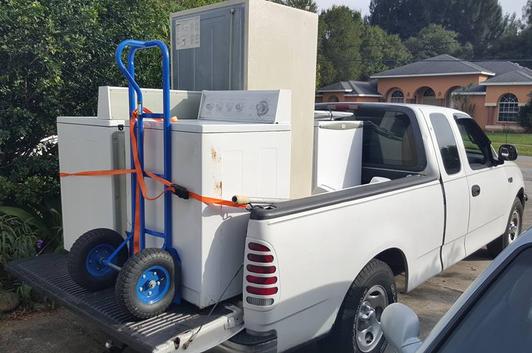 a white pickup truck being used for appliance removal/hauling services
