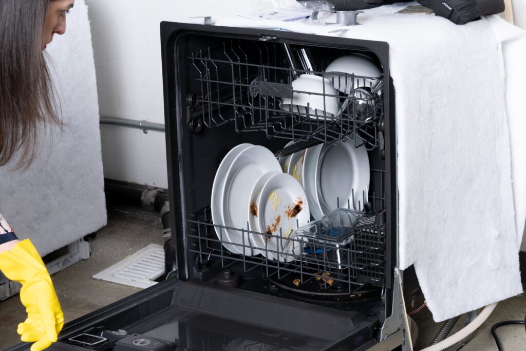 a person loading a dishwasher with dirty dishes