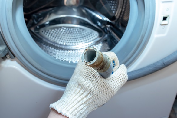 a person holding a washing machine drain hose connection point, likely for inspection or maintenance
