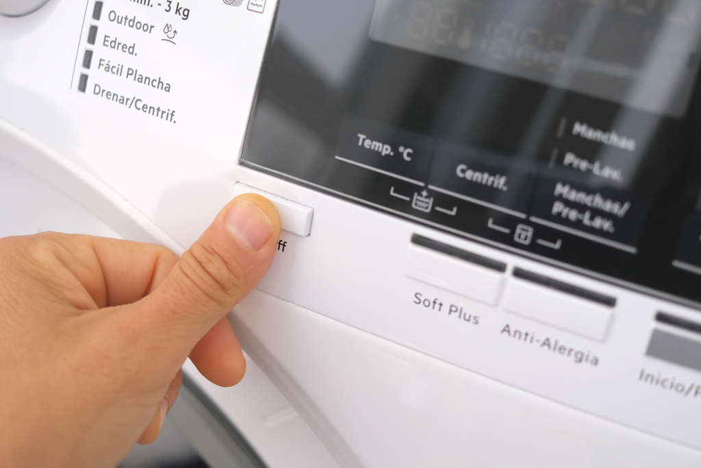 a person's finger pressing a button on an AEG washing machine