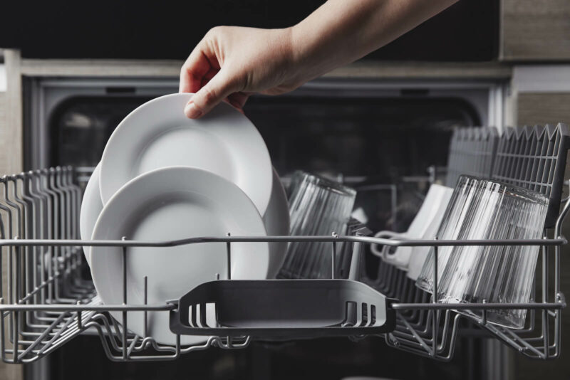 a person loading or unloading clean dishes from a dishwasher