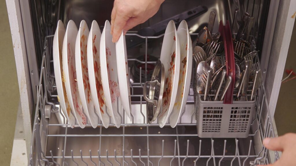 the interior of a dishwasher being loaded with dirty plates and silverware