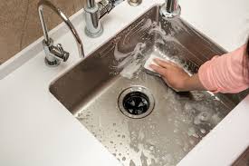 a person cleaning a stainless steel kitchen sink
