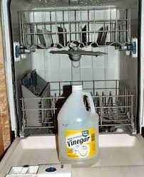 a bottle of white vinegar placed inside an empty dishwasher, illustrating a common method for cleaning the appliance