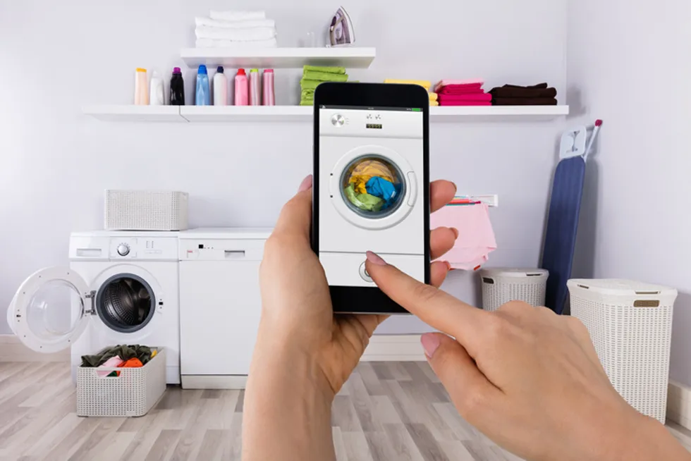 a person using a smartphone to control a smart washing machine