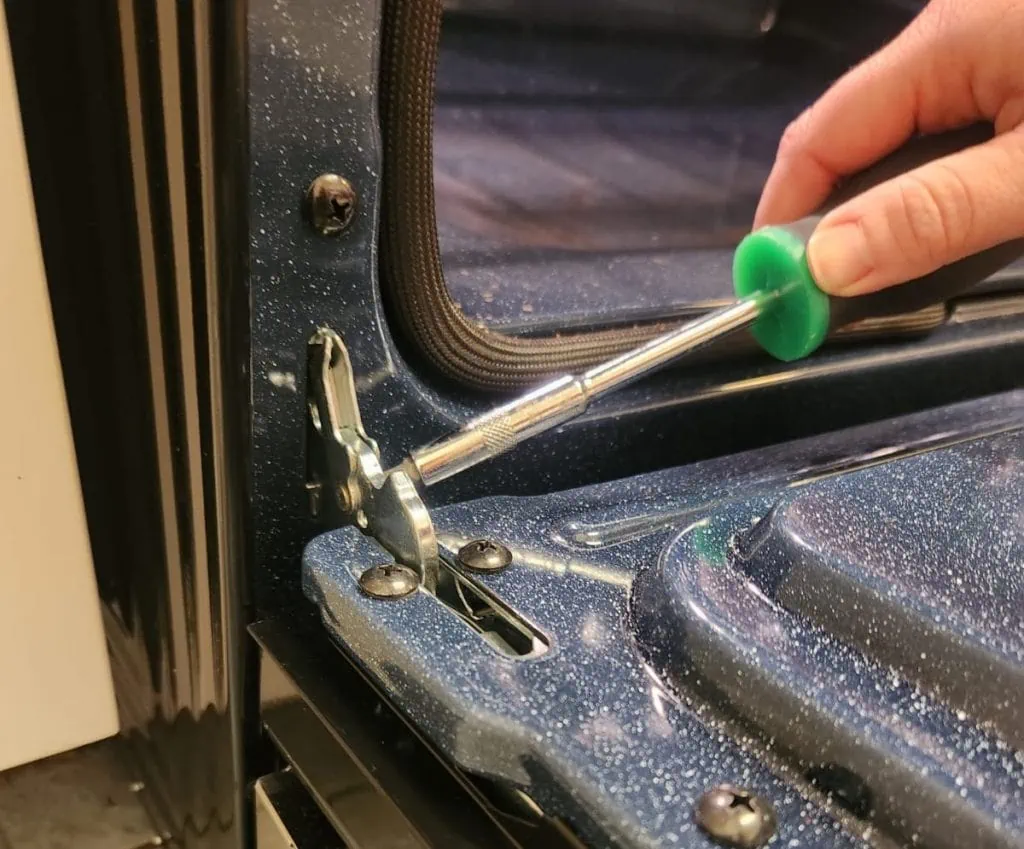 process of servicing or adjusting an oven door hinge