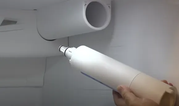 a refrigerator water filter being inserted into its housing