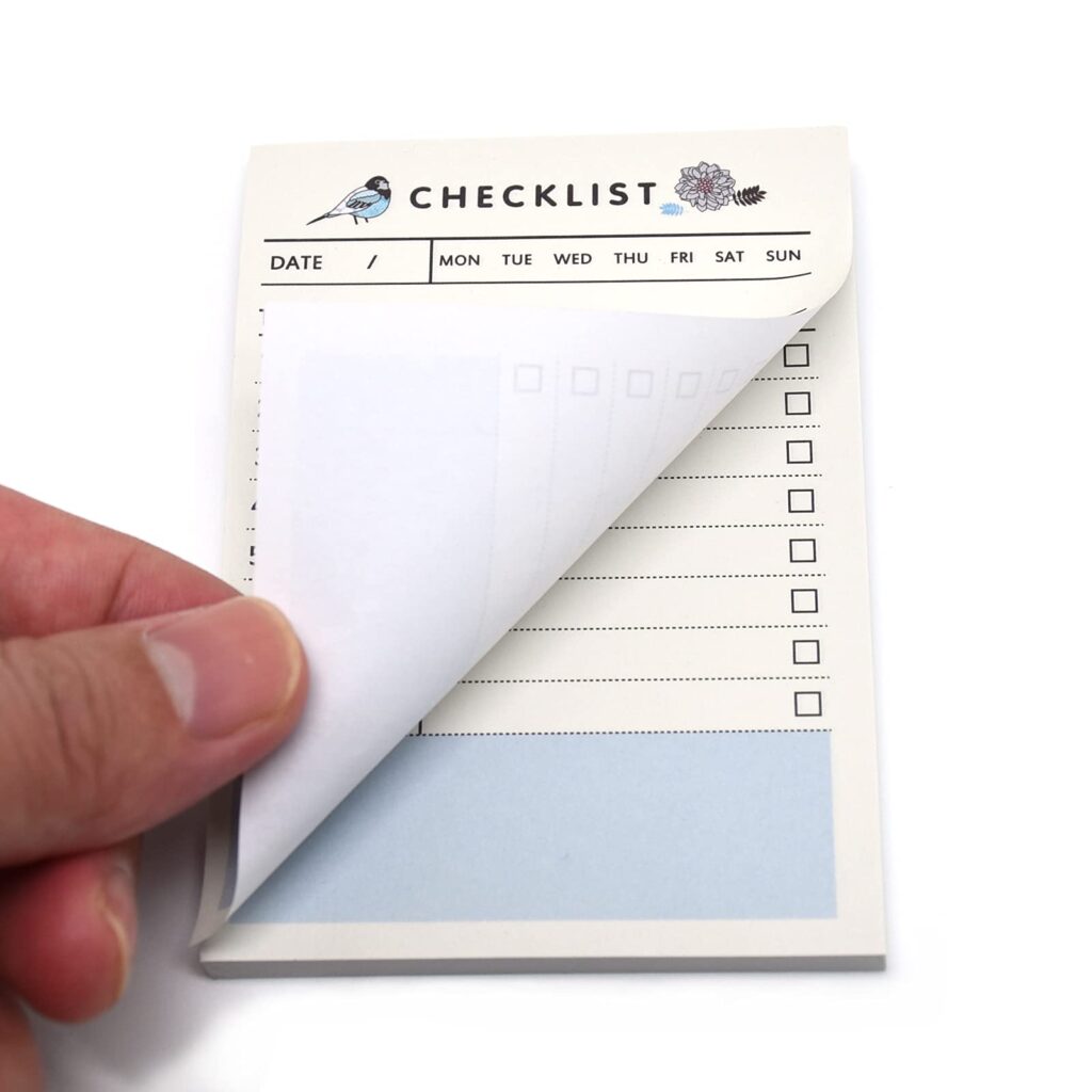 a person holding a small, unbranded checklist memo pad or sticky notes pad