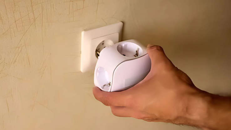 a hand inserting a smart plug into a wall socket